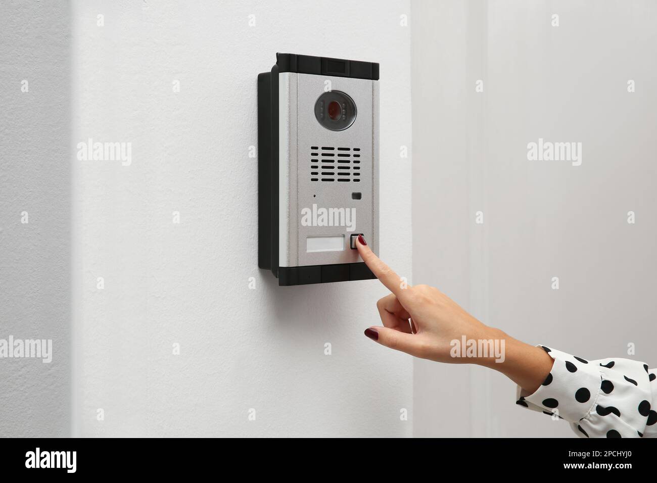 African-American woman ringing intercom with camera in entryway, closeup Stock Photo