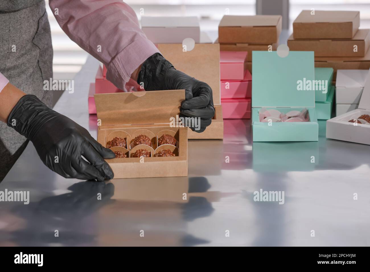 Delicious Packing Woman packing delicious candies into box at production line, closeup ...