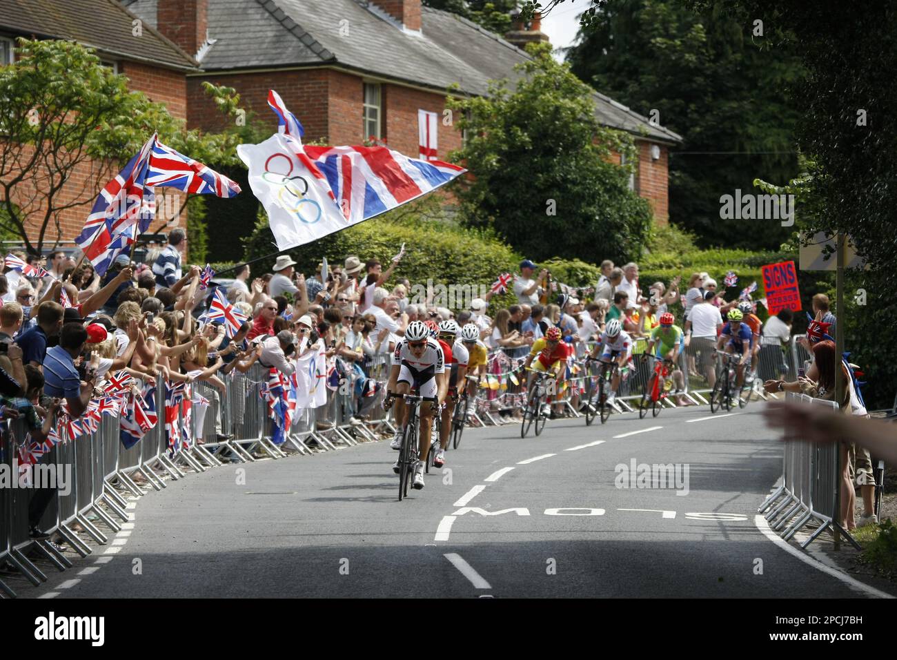 August 2012 Headley, Surrey, UK  The Olympic Cycle race peloton rides through a fervently patriotic crowd in the village of Headley. Stock Photo