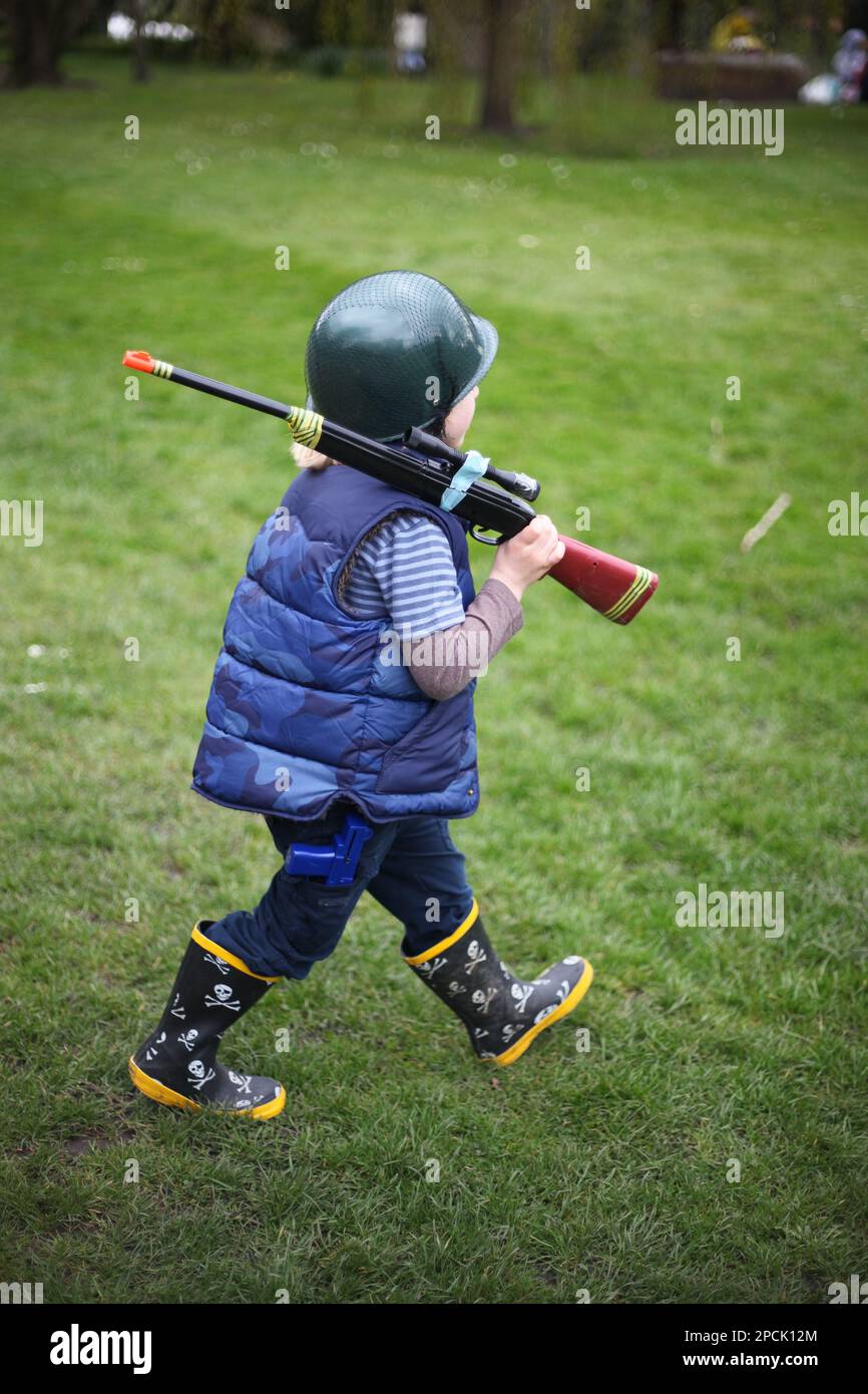 Young boy carrying a toy gun Stock Photo Alamy