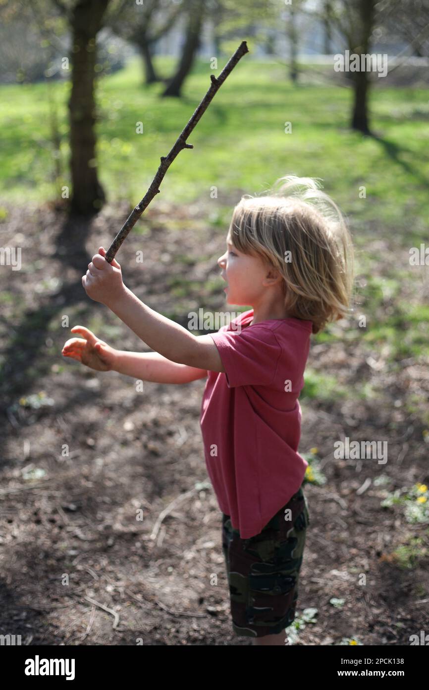 Young boy playing outdoors with a stick Stock Photo