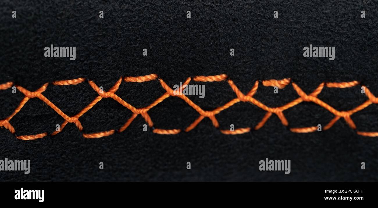 Orange stitches on alcantara sport car wheel close up view Stock Photo