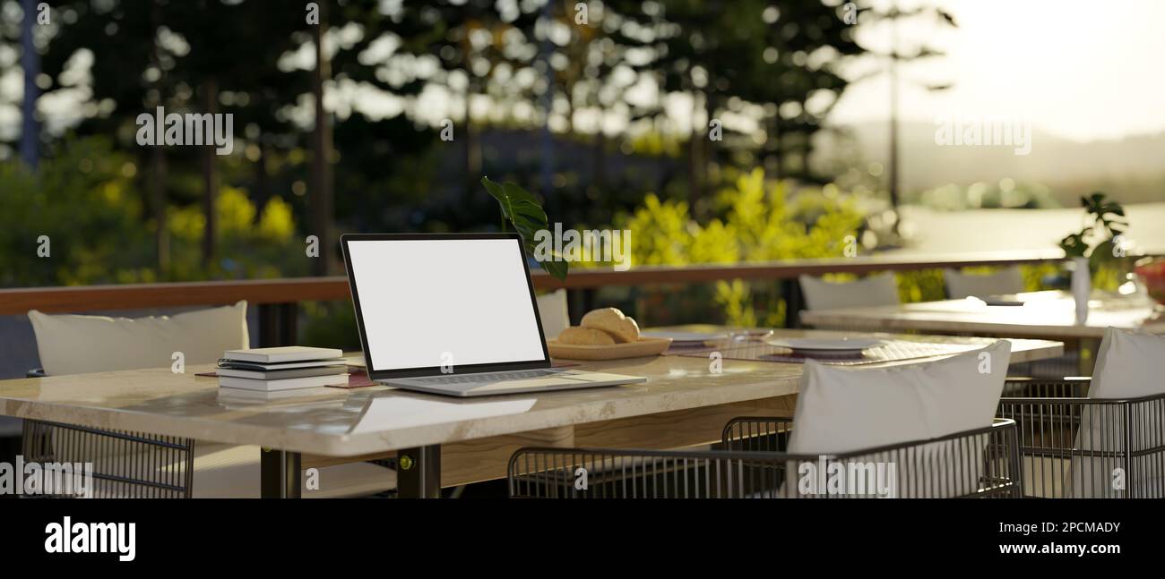 Laptop white screen mockup on beautiful outdoor dining table with ...