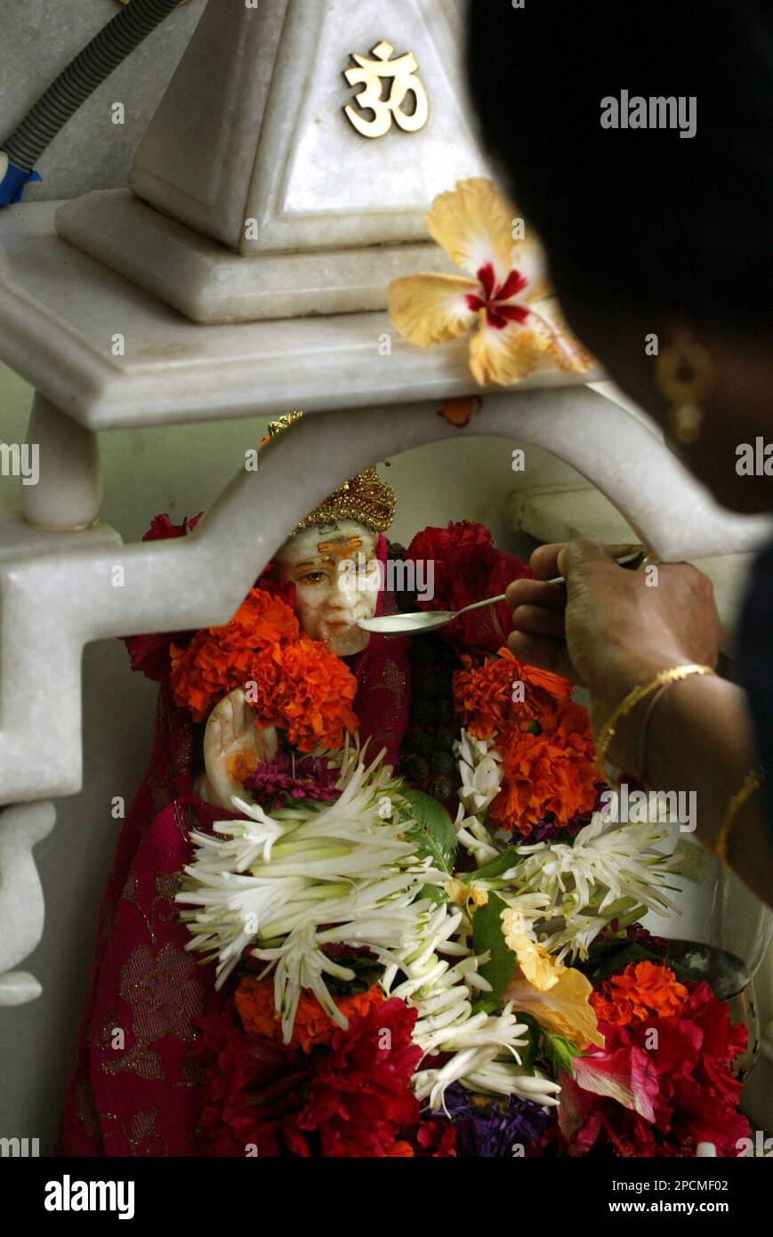 A devotee offers milk with a spoon to an idol of Indian saint Shirdi