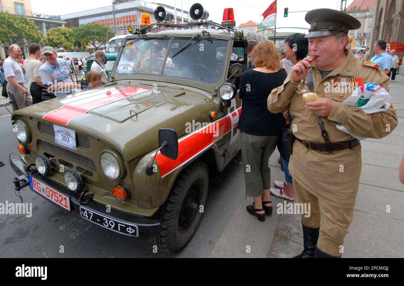 Dieter Brundisch, rechts, in der Uniform eines Offiziers der Roten Armee  steht essend neben einem Gelaendewagen UAZ-469B der sowjetischen  Streitkraefte in der DDR, Baujahr 1982, waehrend des Treffens von etwa 200  Fahrzeugen