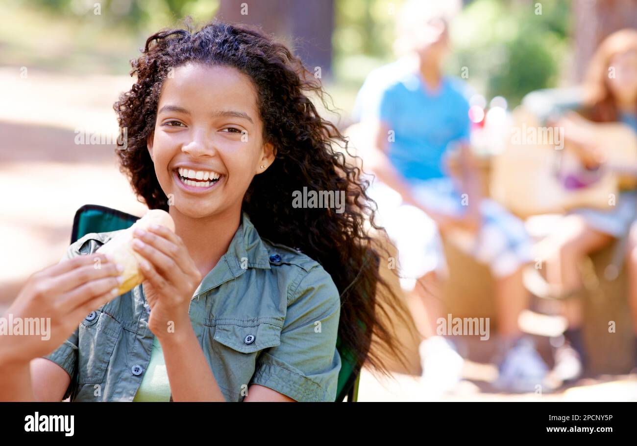 Mmm, it looks so tasty. A cute little girl eating a hotdog while smiling. Stock Photo