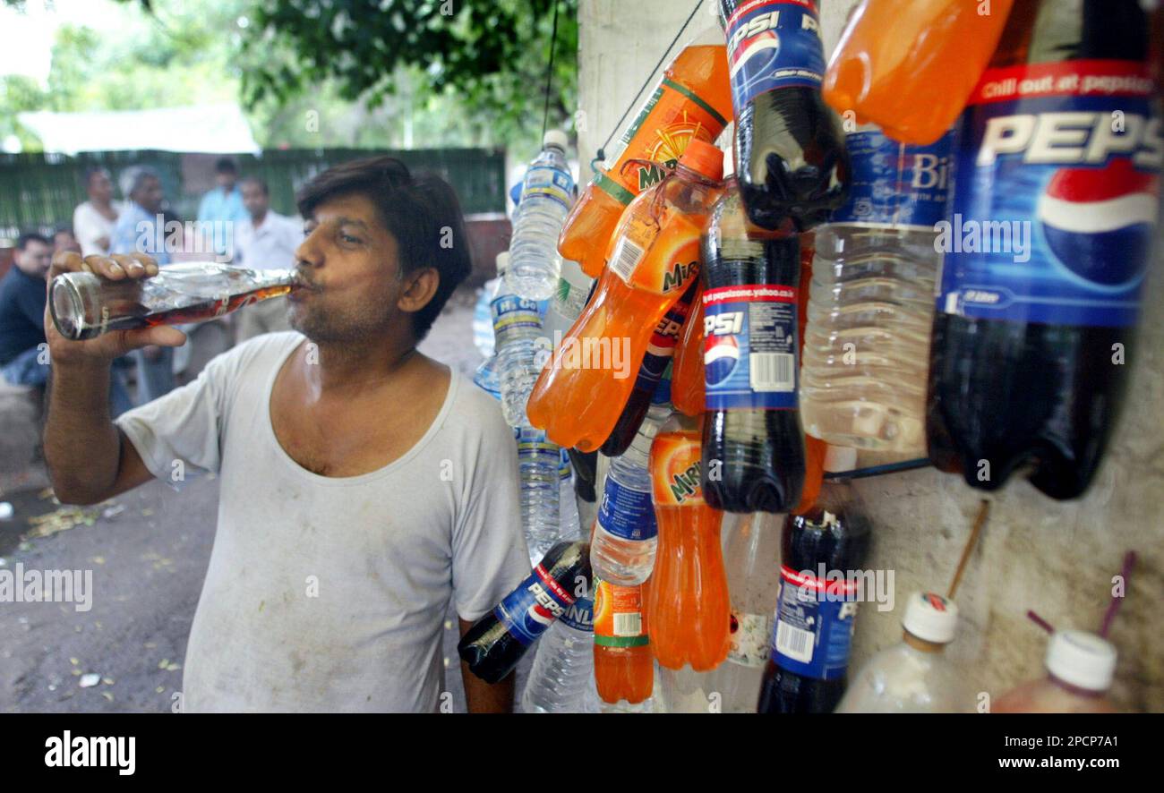 A man drinks a soft drink outside a shop, in New Delhi, India, Thursday