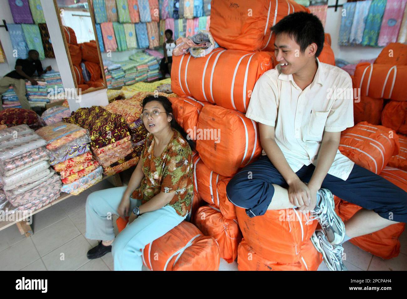 Two unidentified Chinese traders sits on clothing materials for 