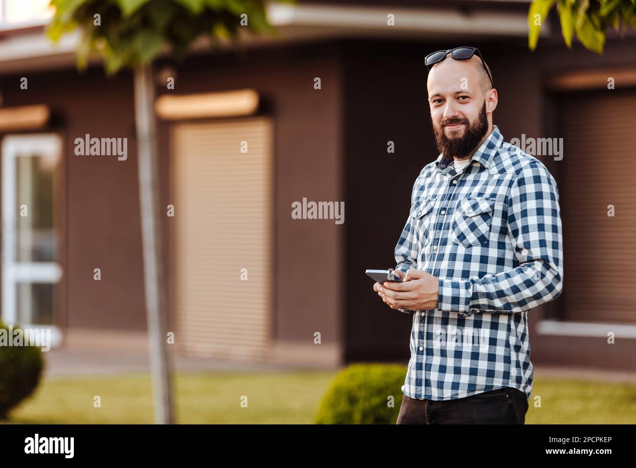 A young man walks in the park and uses social networks using a mobile phone. Stock Photo