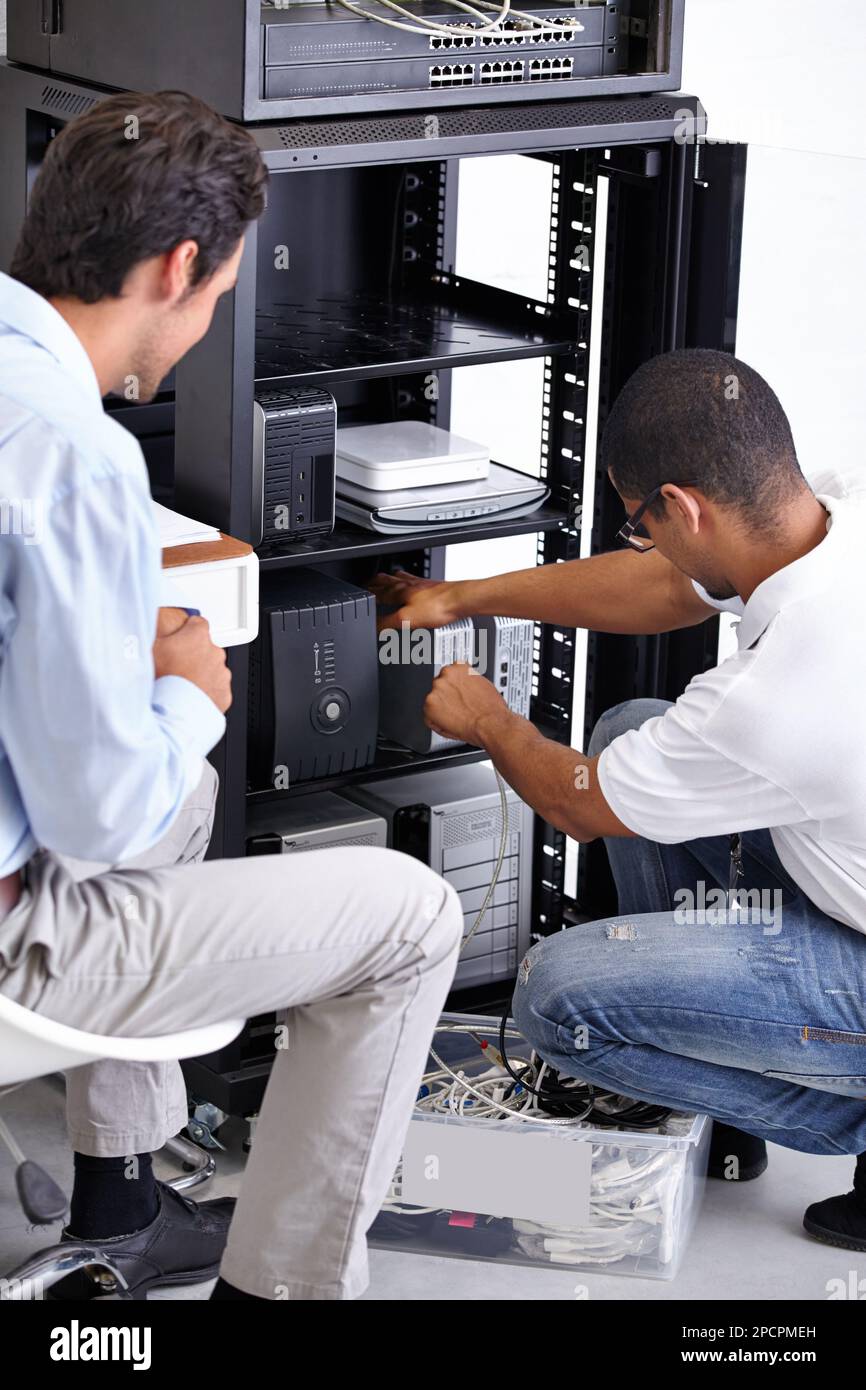 Finding the problem and fixing it. Two IT professionals working on a server. Stock Photo