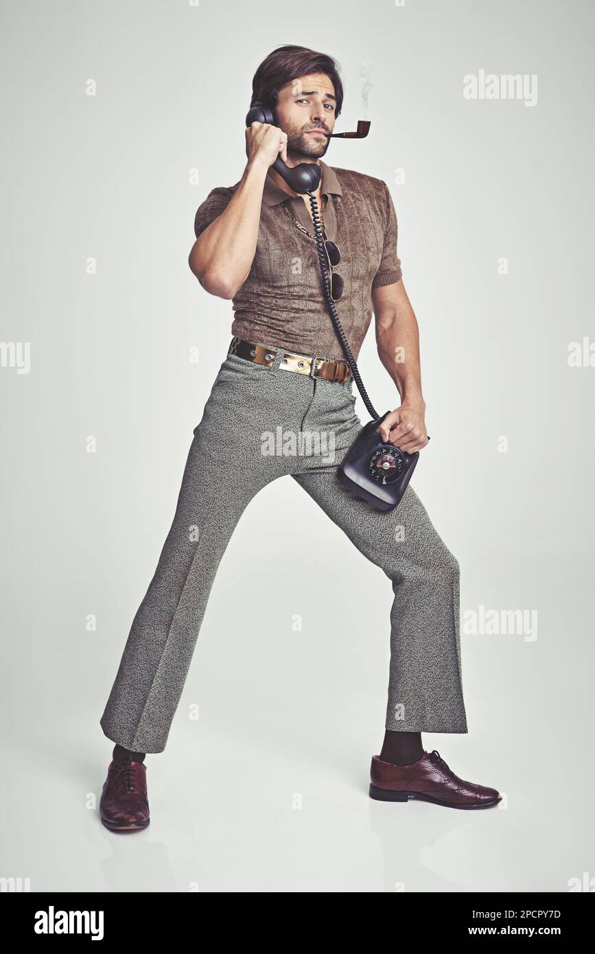 Doing everything with flair. A handsome man on a retro telephone while striking a pose. Stock Photo
