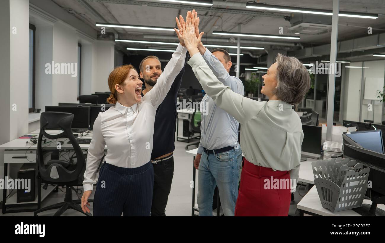 Four co-workers give a high five in the office Stock Photo - Alamy