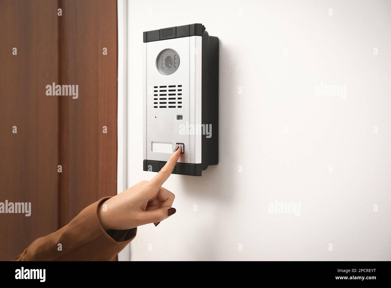 African-American woman ringing intercom with camera in entryway, closeup Stock Photo