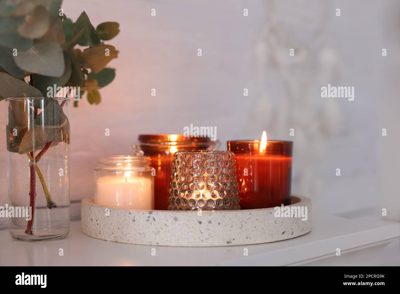 Burning candles on mantel near white wall indoors Stock Photo Alamy