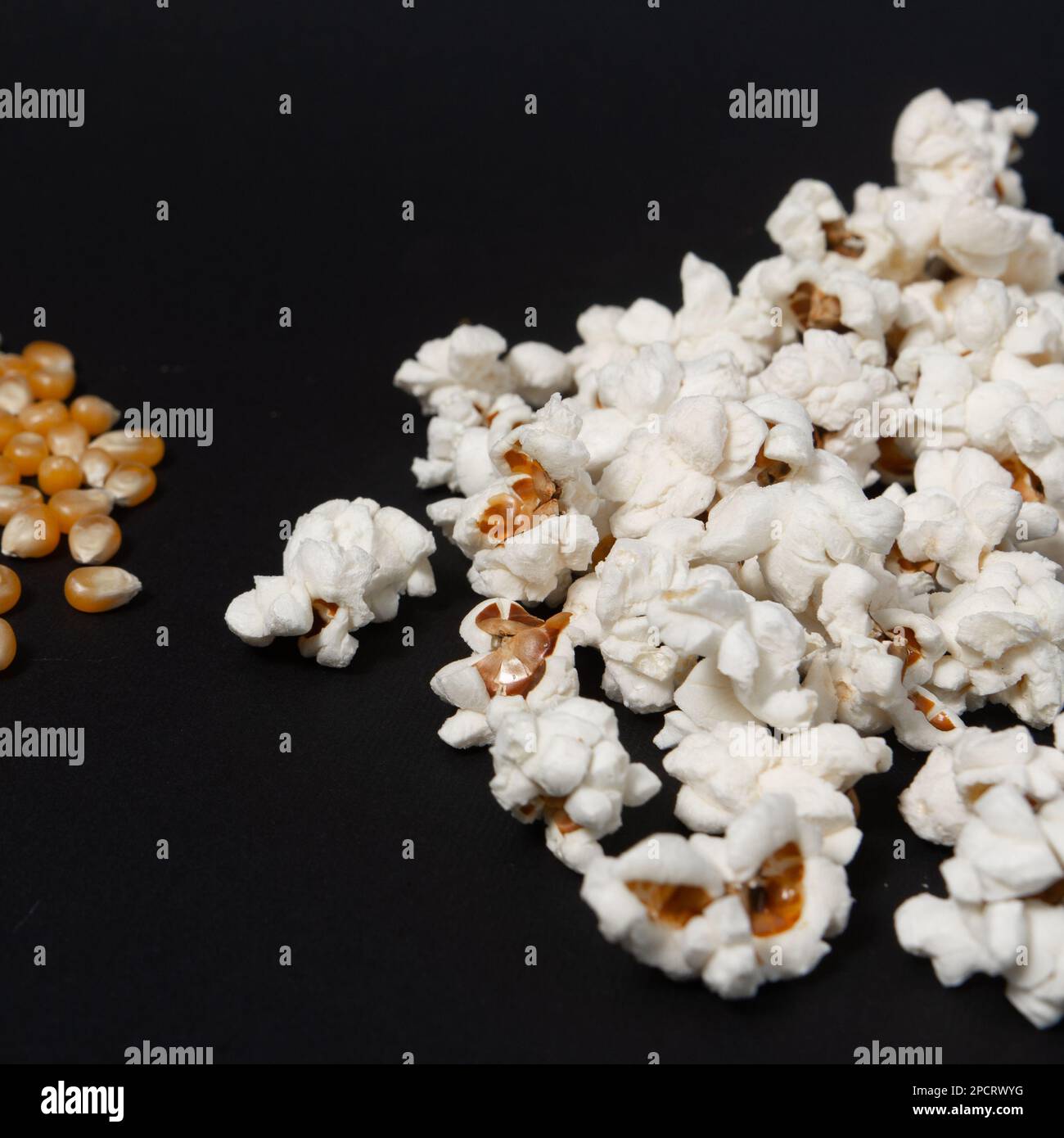 Two piles of popcorn, one pile of ready popcorn, another with corn