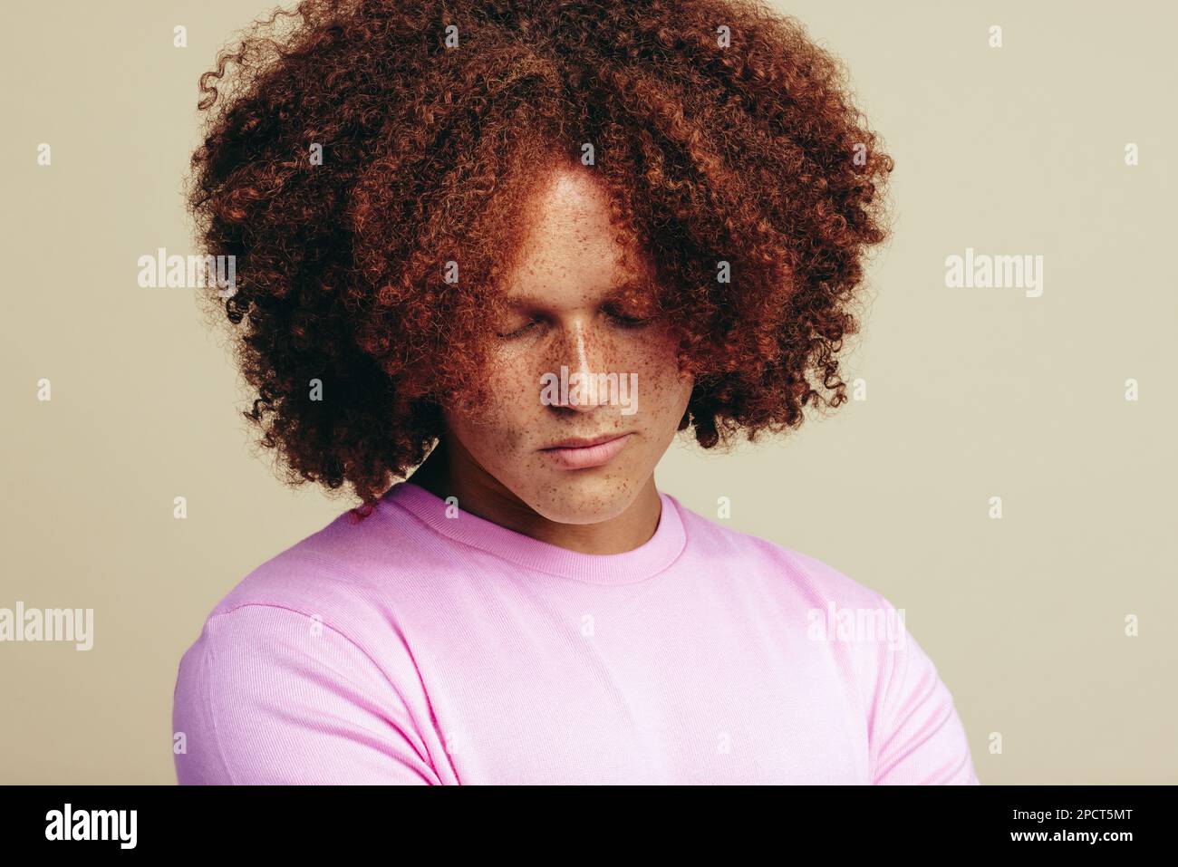 Man with red hair and freckles on his face stands in a studio, radiating self-confidence and self-acceptance. Youthful and handsome man embracing his Stock Photo