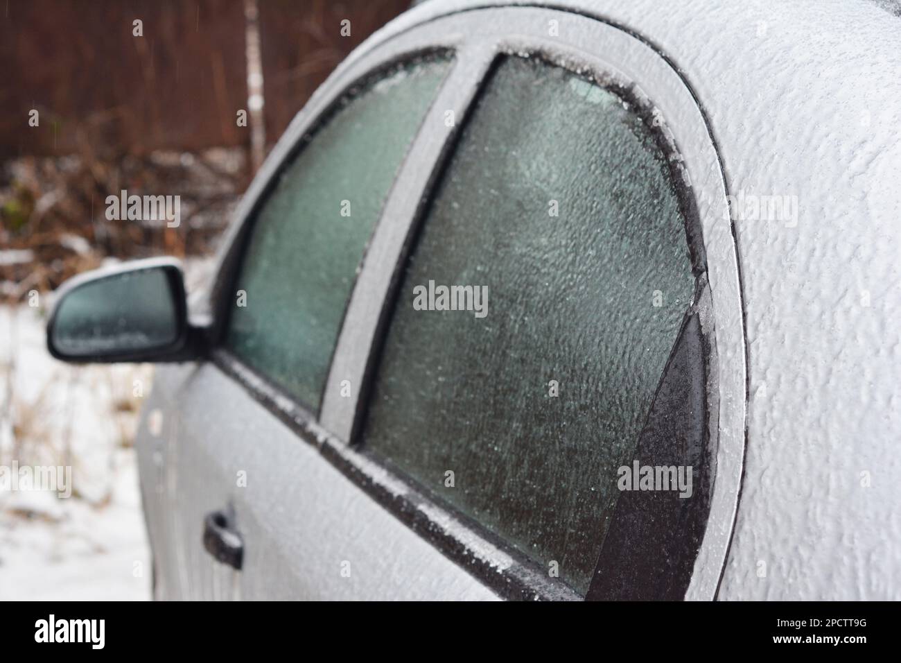 A closeup of a car with frozen windows and doors after ice storm in