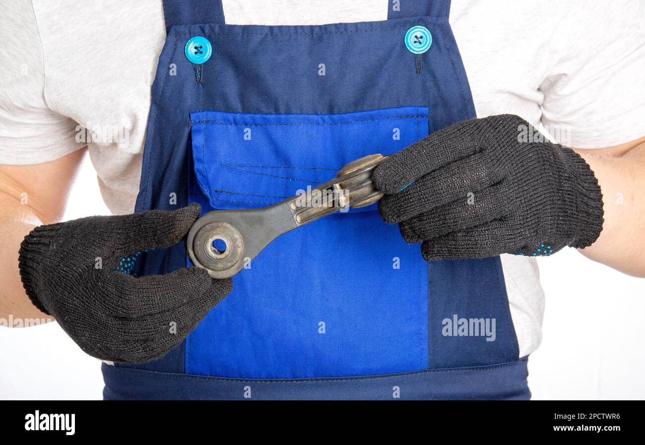 A car mechanic holds in his hands a part of a car suspension, a