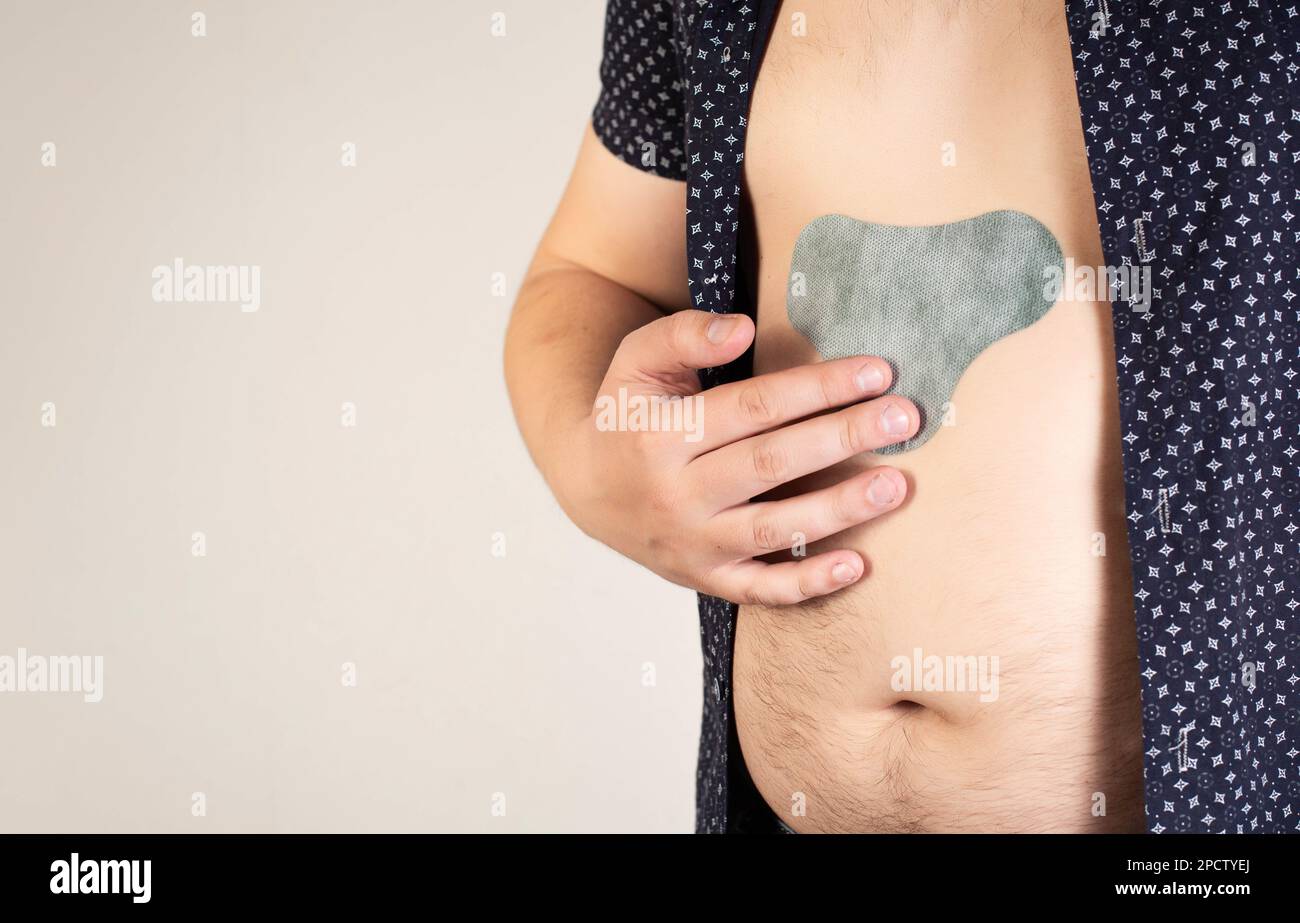 https://c8.alamy.com/comp/2PCTYEJ/a-man-in-a-black-shirt-sticks-an-anesthetic-patch-on-his-stomach-relieve-pain-and-tension-bactericidal-2PCTYEJ.jpg
