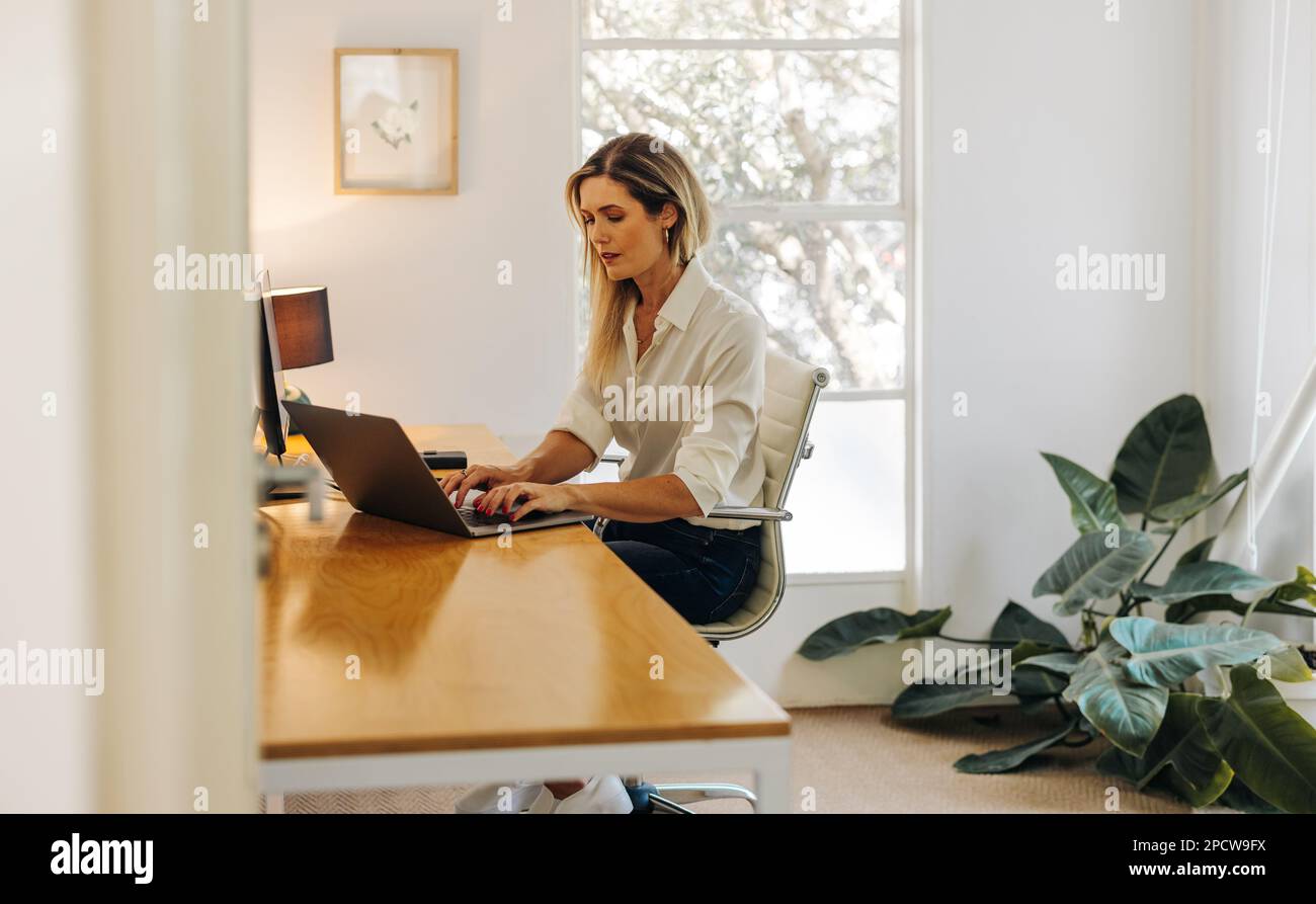 Female entrepreneur typing on a laptop keyboard while sitting in her ...