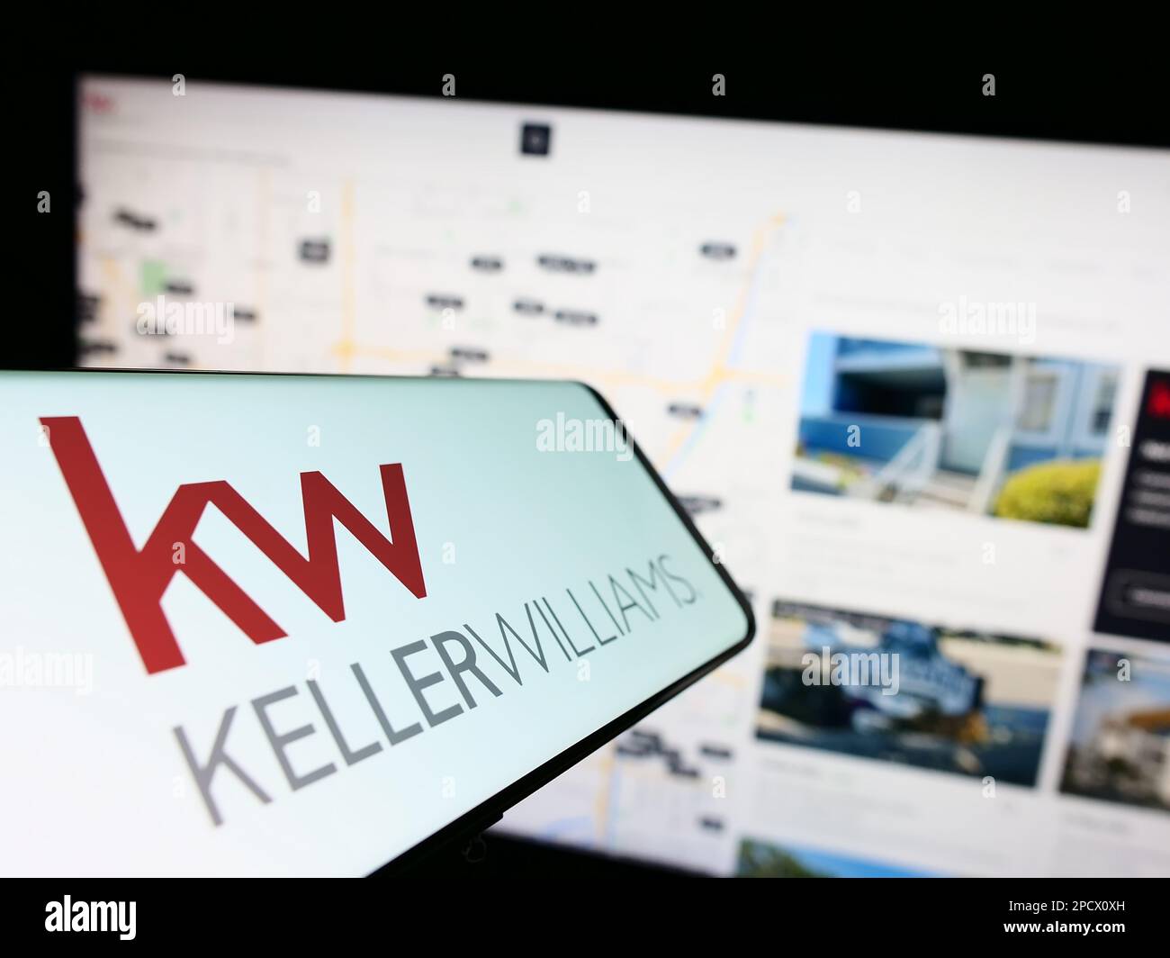 Smartphone with logo of real estate company Keller Williams Realty Inc. on screen in front of website. Focus on center-left of phone display. Stock Photo