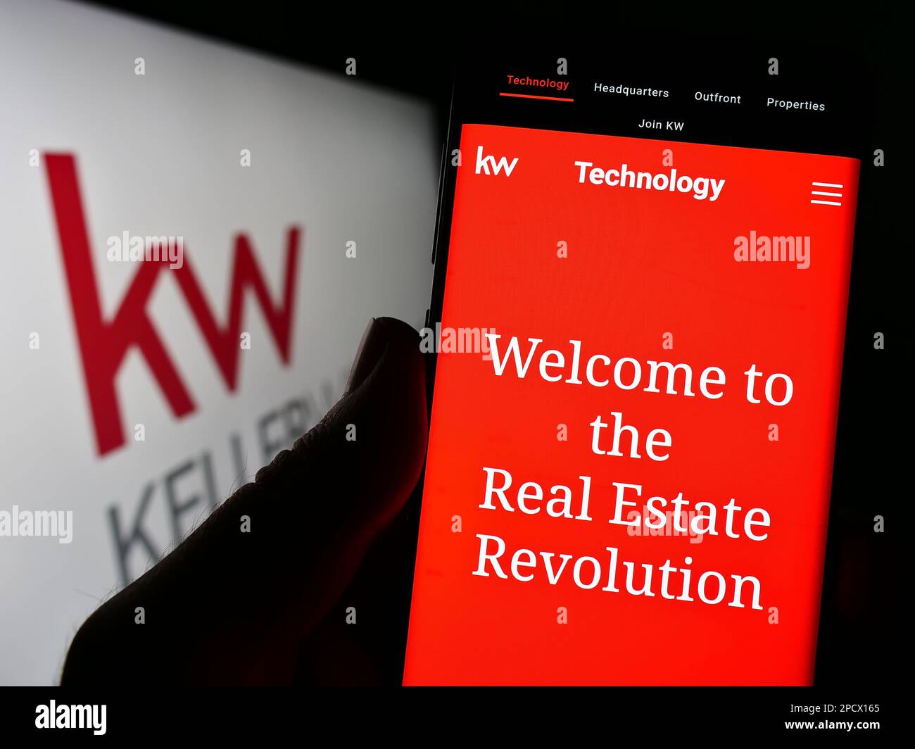Person holding cellphone with webpage of real estate company Keller Williams Realty Inc. on screen with logo. Focus on center of phone display. Stock Photo