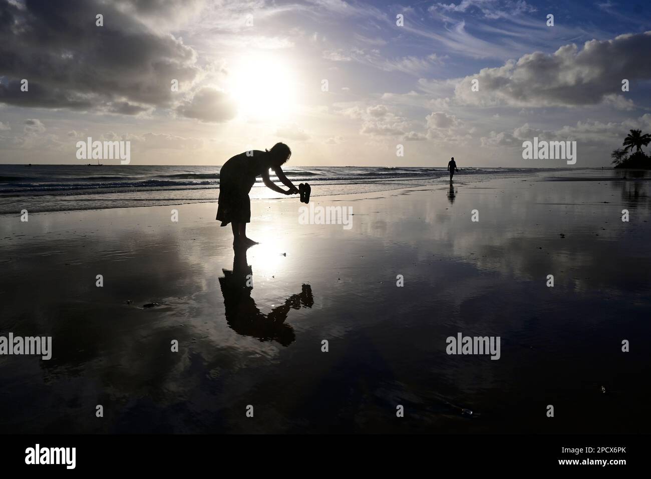 Woman silhouette on wet beach at dawn, Inhassoro, Mozambique, Africa Stock Photo
