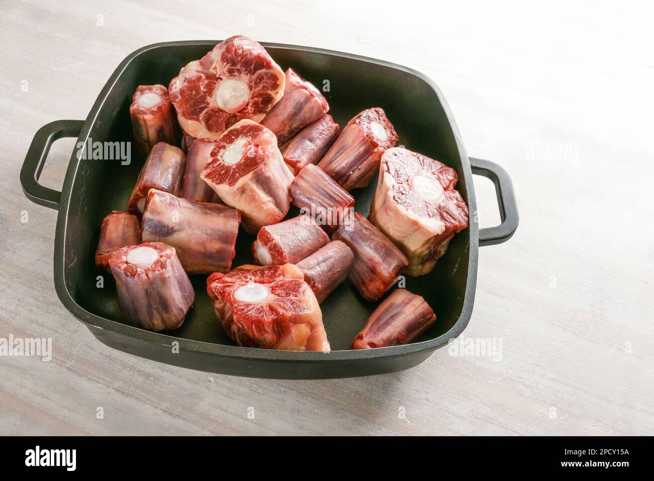 Raw oxtail pieces with bone in a black tray, gelatin-rich meat traditional for a slow-cooking stew or stock base for oxtail soup, copy space, selected Stock Photo
