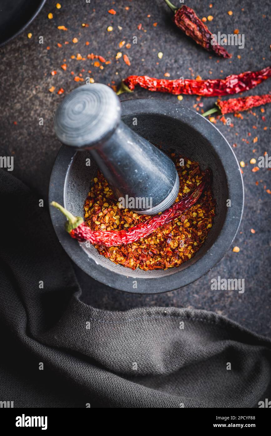 Dry chili pepper flakes. Crushed red peppers in mortar on the black