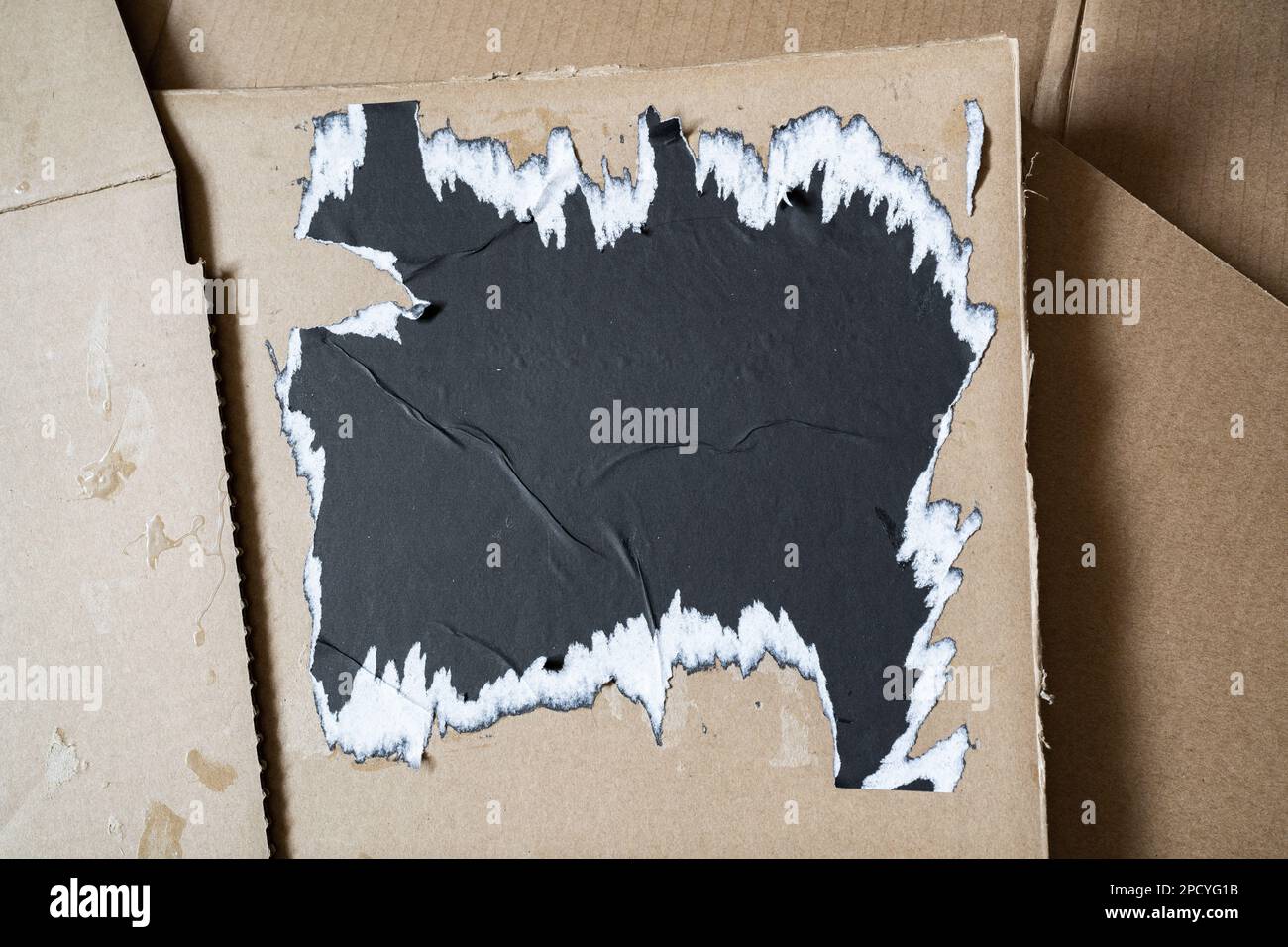 Ripped black square paper on cardboard background Stock Photo