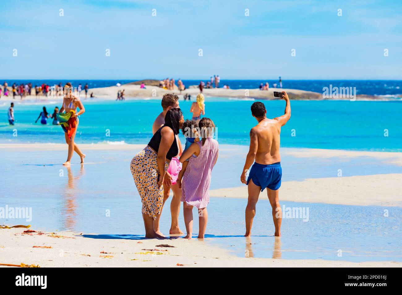Cape Town, South Africa - February 18, 2023: Young family on Camps Bay beach shore Stock Photo