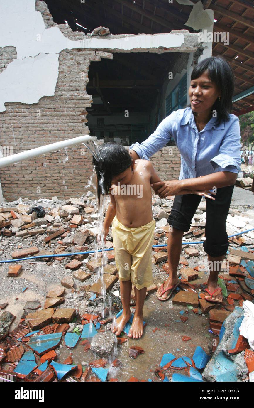 A mother helps her daughter to take shower at a damaged school in Banyusoco  village near Gunung Kidul, Indonesia, Wednesday, June 7, 2006. Indonesia  kicked off a campaign to immunize more than