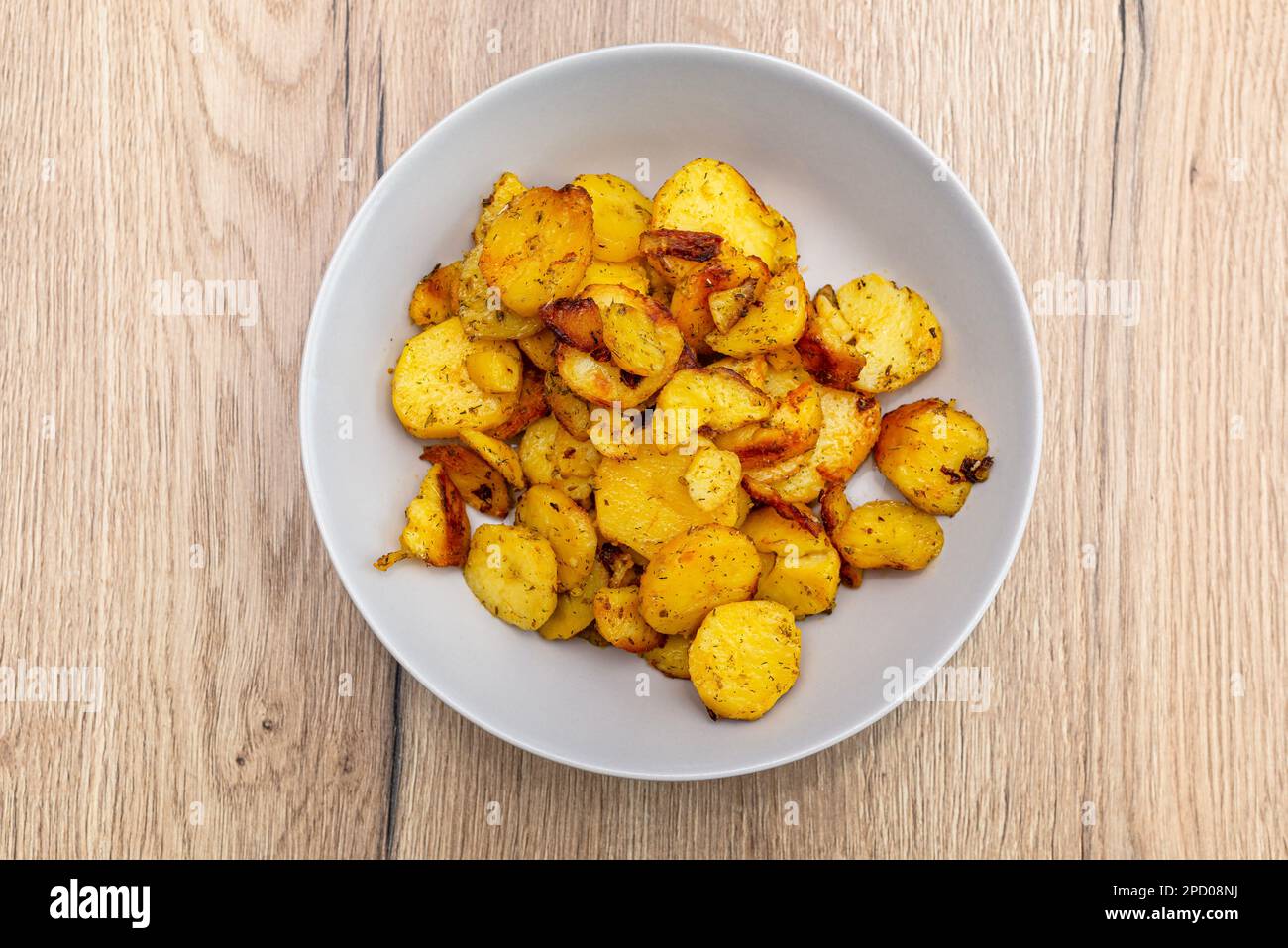 Boiled potatoes and later baked in slices on the grill, lying in a round plate. Stock Photo