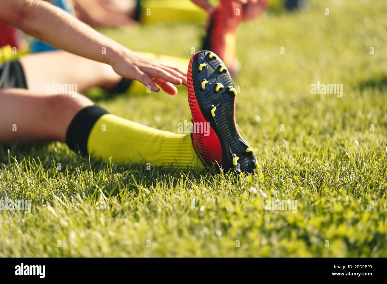 Soccer Player Stretching Legs. Football Player in Cleats Doing Stretching Exercises During