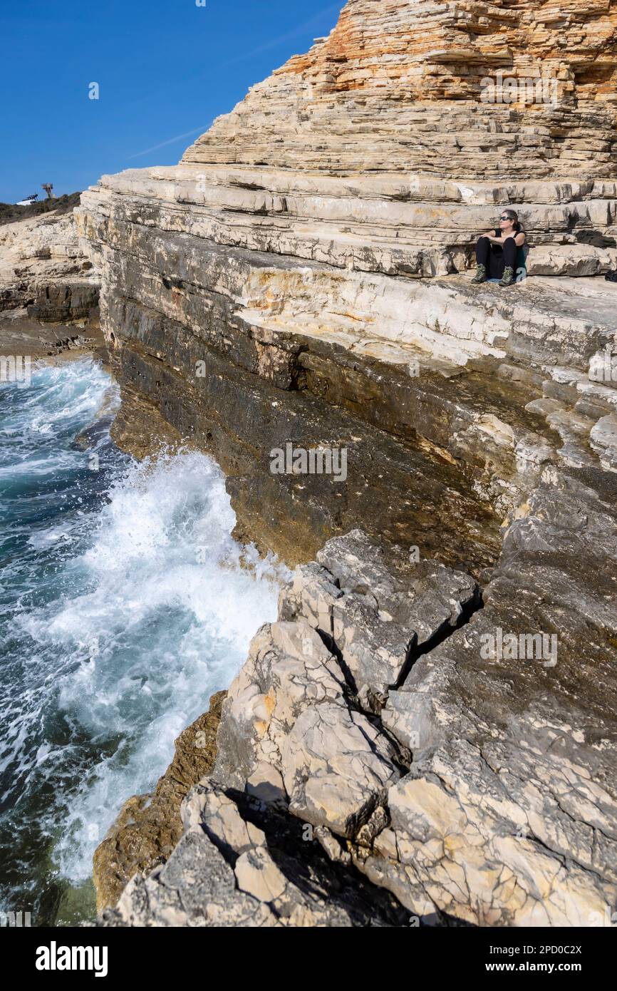 woman lying on the rocks of Cape Kamenjak, a protected natural area on the southern tip of the Istrian peninsula in Croatia, Europe Stock Photo