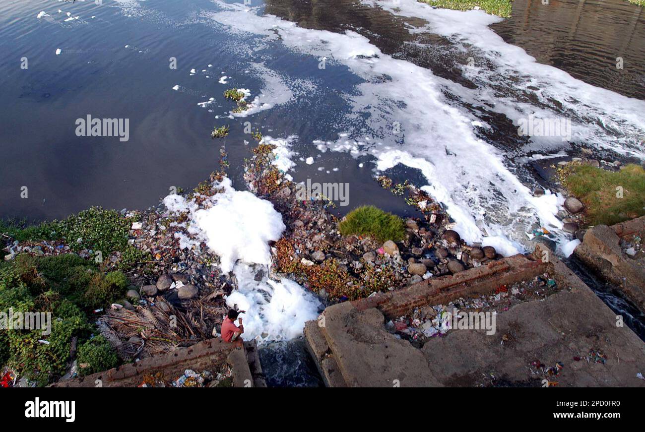 A boy sits on the bank of Cooum River in Madras, India, Sunday, June 4, 2006. The Cooum river