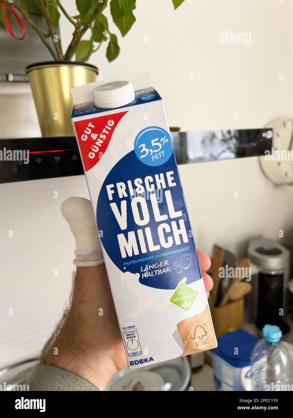 France - May 29, 2022: POV male hand holding Edeka Gut und Gunstig Fresh 3,5 whole milk - kitchen background Stock Photo