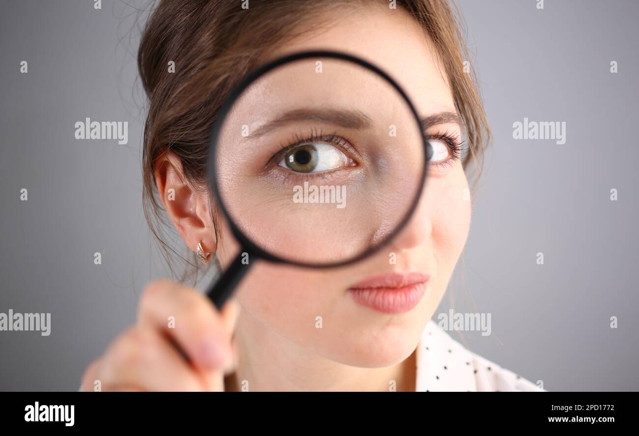 Inquisitive young woman looking through magnifying glass Stock Photo ...