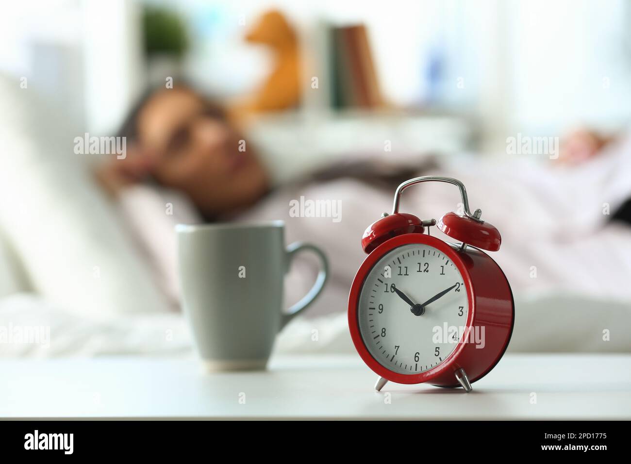 Red alarm clock at ten o'clock and sleeping woman Stock Photo