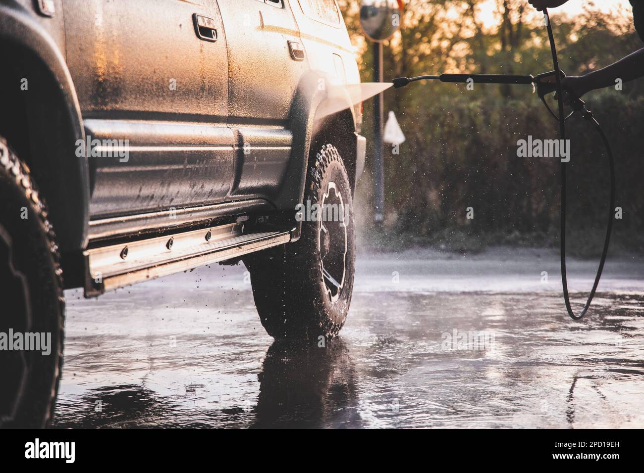 Washing SUV car at a selfservice car wash with a highpressure water jet after offroad driving