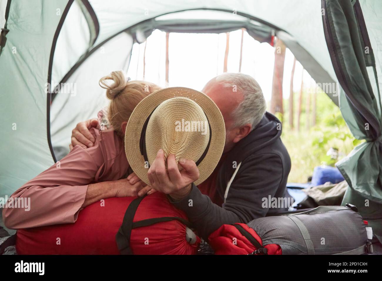 Elderly Couple Covering Face With Hat While Kissing Each Other In Camping Tent At Forest Stock 