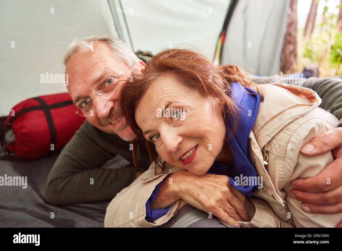 Happy senior couple in love lying in tent on camping site in nature Stock Photo