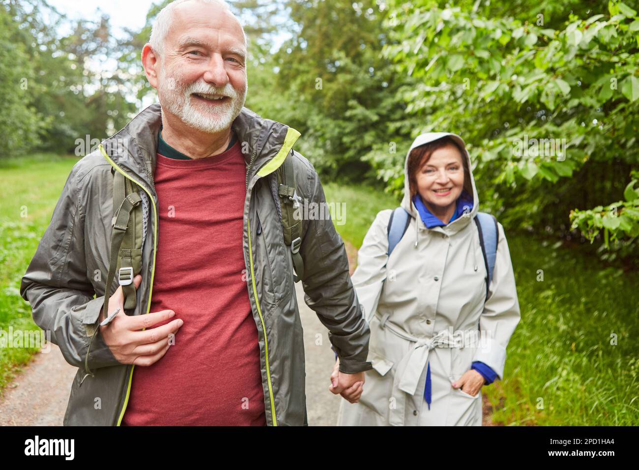 Portrait of cheerful elderly couple in jackets exploring forest during vacation Stock Photo