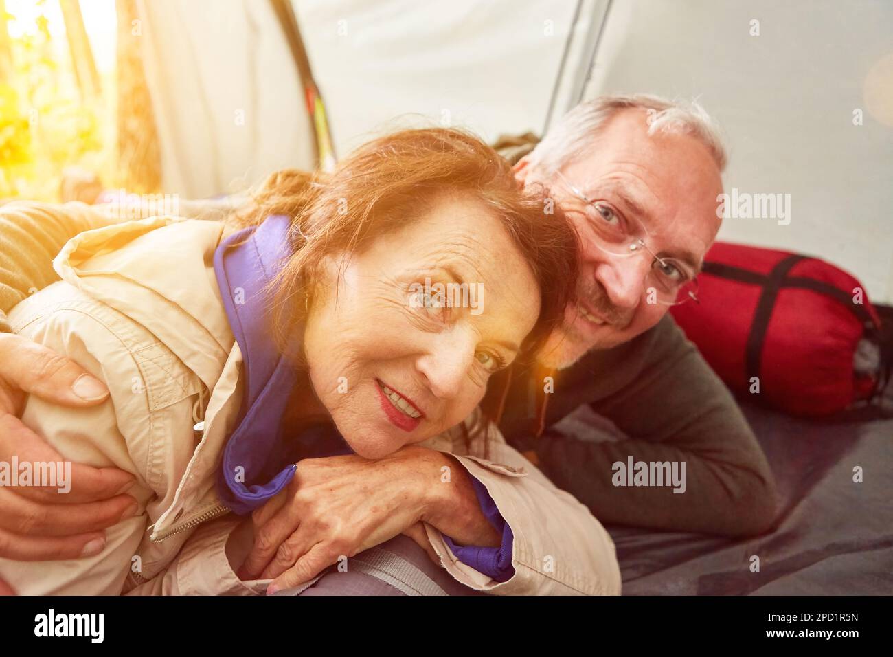 Happy senior couple in love lying in tent on camping site in summer Stock Photo