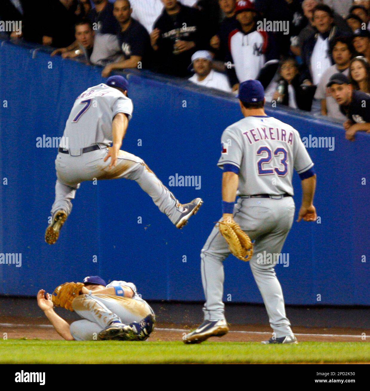 Texas Rangers' Mark DeRosa (7) leaps over Kevin Mench as Mark Teixeira (23)  looks on after Mench made a diving catch on a fly ball by New York Yankees'  Bubbba Crosby in