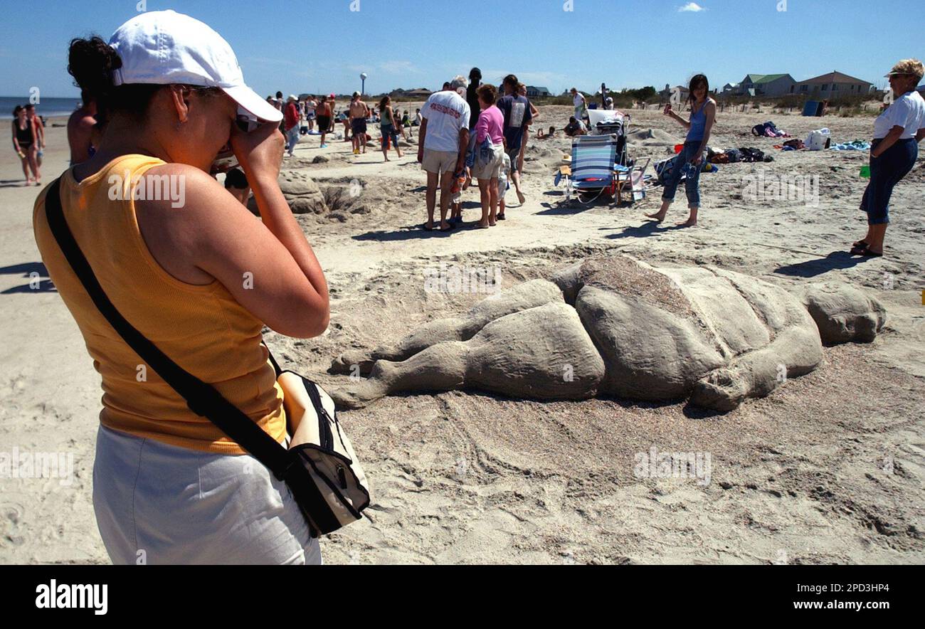 Lucy Lopez of New York snaps a photo of a sand sculpture depicting a woman  in a bikini during the Savannah College of Art and Design Sand Art Festival  on the North