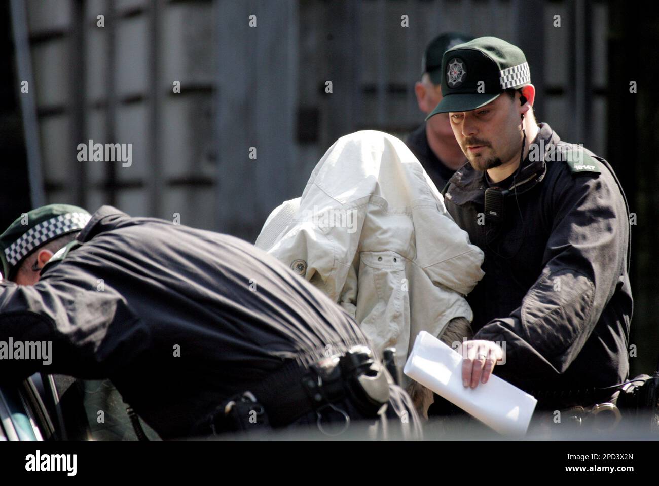 One of the five people charged with murder is led away by police from Ballymena court, Northern