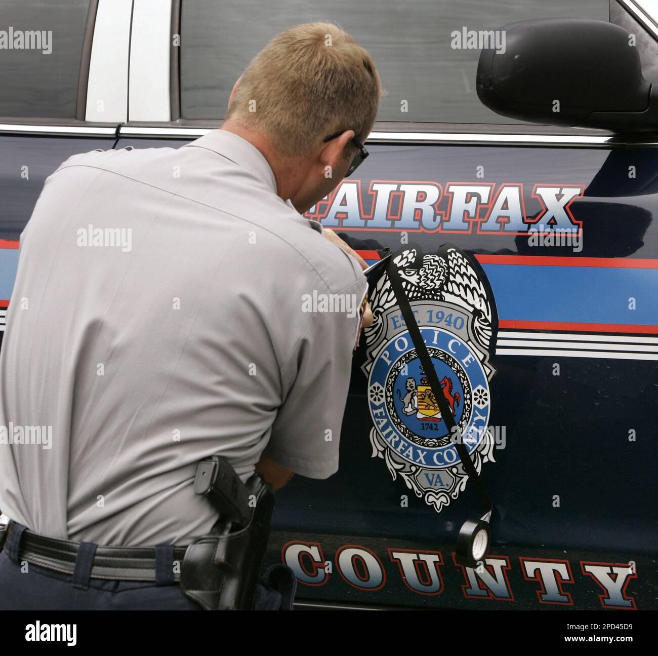 Fairfax County master police officer Wayne Compher puts black tape on a