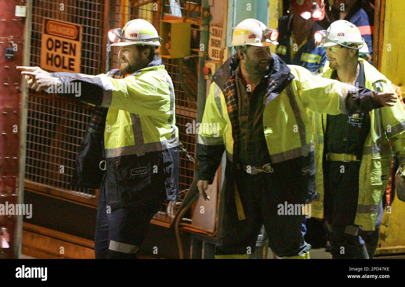 Miners Todd Russell, left, and Brant Webb, center, take their first steps above ground after spending two weeks trapped nearly a kilometer (3,000 feet) underground in the Beaconsfield Gold Mine at Beaconsfield, Australia, Tuesday, May 9, 2006. After initial medical tests underground, Webb, 37, and Russell, 34, strode purposefully from the mine's main lift shaft and hugged family and friends before clambering into two ambulances, still laughing and joking with friends. (AP Photo/Ian Waldie, Pool) Stock Photo
