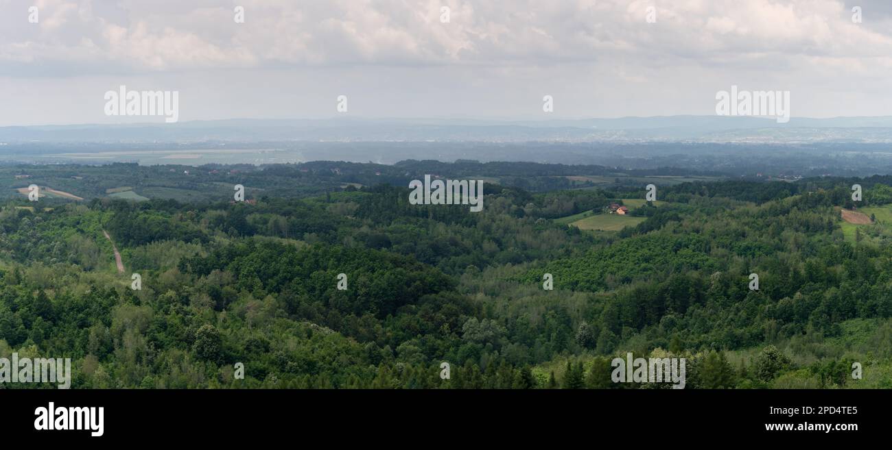 Hilly landscape with lush forests and scattered village during rainy ...